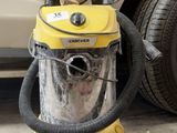 un aspirateur jaune posé par terre à côté d'une voiture