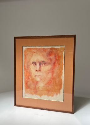 peinture représentant le visage d'un homme, dans un cadre marron, sur un fond blanc
