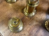 trois bougies en laiton posées sur une table en bois recouverte d'une nappe à carreaux rouges et blancs