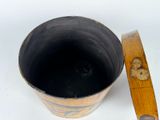 a black bucket with a wooden handle on a white surface