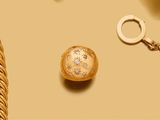une photo montrant un collier en or et une boule en or posés sur une table