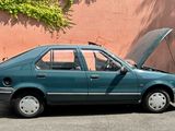 a blue car with its hood open parked in front of a pink wall