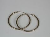two pairs of silver hoop earrings on a white surface