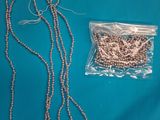 a close up of a necklace and a bag of beads on a blue surface