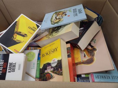 une boîte remplie de livres posés sur le sol