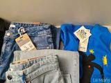 a pile of clothing that includes a t - shirt, jeans, and a pair of shoes