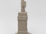 sculpture of a hand holding a bird on a pedestal