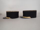 pair of black top hats with gold trims sitting on a table