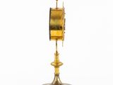 an image of a gold clock on a stand on a white background