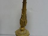 a gold candle holder on a table with a white wall in the background