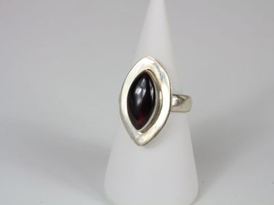 a close up of a silver ring with a red stone in it