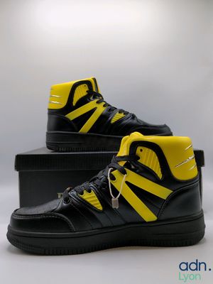 a pair of black and yellow sneakers sitting on top of a box