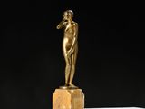 une statue antique en bronze représentant une femme, posée sur un bloc de marbre