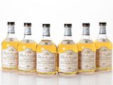 four bottles of whisky are lined up in a row on a white surface
