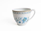 a white cup with blue flowers on it on a white surface