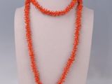 an orange beaded necklace is displayed on a mannequin