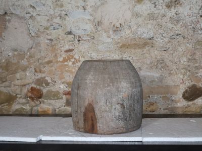 un vase en bois posé sur une table devant un mur en pierre