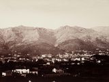 a black and white photo of a town with mountains in the background