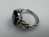 a close up of a ring with a purple stone surrounded by green and yellow stones