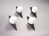 trois appliques murales noires et blanches fixées sur un mur blanc