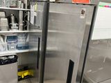 stainless steel refrigerator in a commercial kitchen with lots of dishes on the shelves