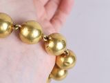 a person holding a bracelet that has gold balls on it