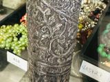 a silver vase on a wooden stick in front of a glass case