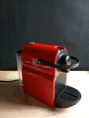 une machine à café rouge posée sur une table en bois