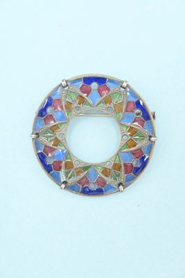 a close up of a colorful broochle on a white surface