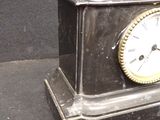 a black clock with a gold face on a black surface