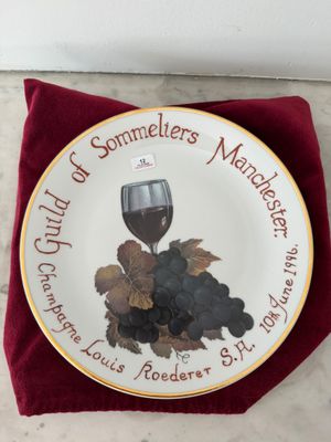 une assiette sur laquelle sont disposés un verre à vin et des raisins