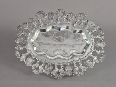 une assiette ancienne en argent, ornée d'un motif floral sur le bord