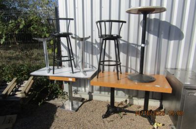 une table avec des chaises et une table avec des tabourets devant un bâtiment