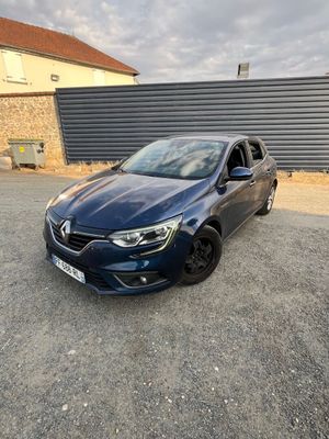 une voiture bleue garée dans un parking à côté d'un bâtiment