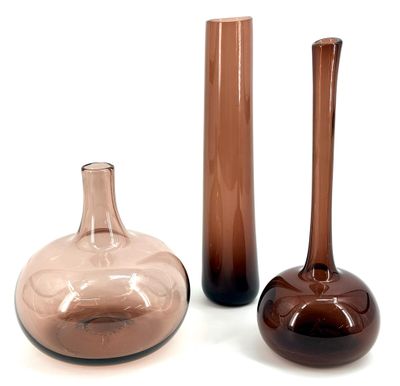 three glass vases sitting next to each other on a white surface