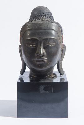 statue représentant une tête de Bouddha posée sur un socle en marbre noir
