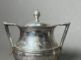 an antique silver teapot with a handle on a gray background
