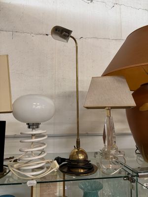 une étagère en verre sur laquelle sont posés une lampe, un abat-jour et un vase
