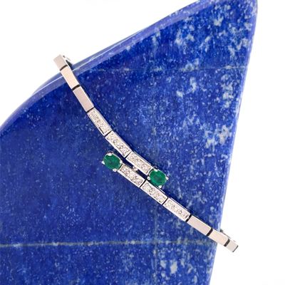 a close up of a blue stone with a diamond and emerald bracelet on it