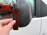 a person holding a ruler in front of a car