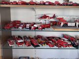 une vitrine remplie de camions de pompiers rouges et blancs et d'autres véhicules miniatures
