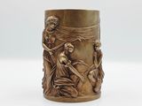 une image représentant un vase en laiton orné d'un motif représentant une femme et un homme