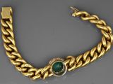 a close up of a gold bracelet with a green stone