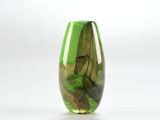 un vase en verre vert contenant des feuilles, posé sur une surface blanche