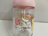 a glass cup with a pink lid on a white table
