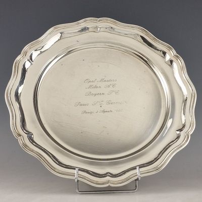 un plat ancien en argent, orné d'une inscription, posé sur un socle