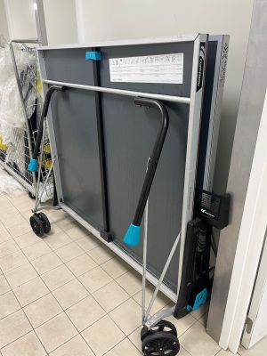 un présentoir métallique muni d'une poignée et de deux roulettes, dans une pièce