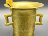 a gold vase with two handles and a wooden spoon in it