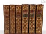 six vieux livres sont alignés sur une surface blanche
