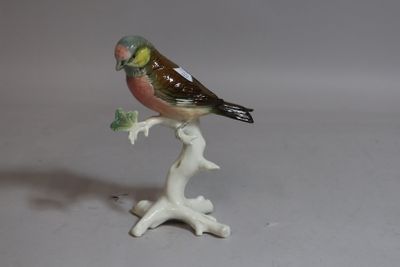 a small figurine of a bird sitting on a branch